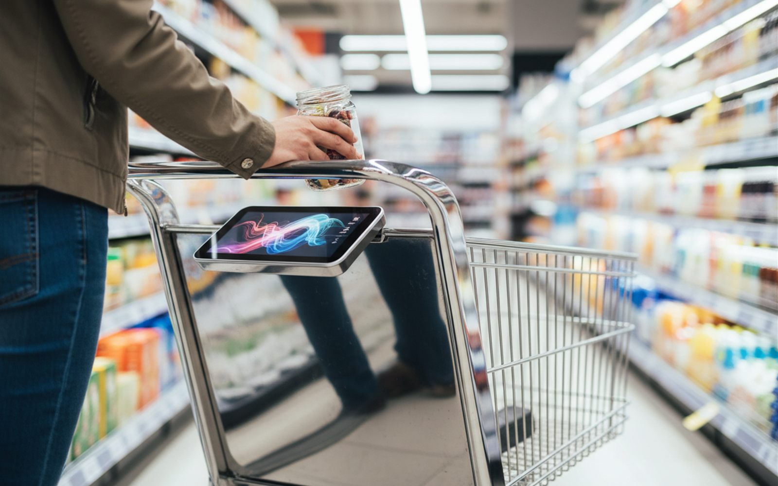 A shopper drops groceries into a smart cart while its handle screen keeps a running total.